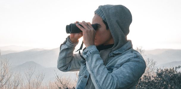 Eine Mensch schaut mit einem Feldstecher in die Ferne.